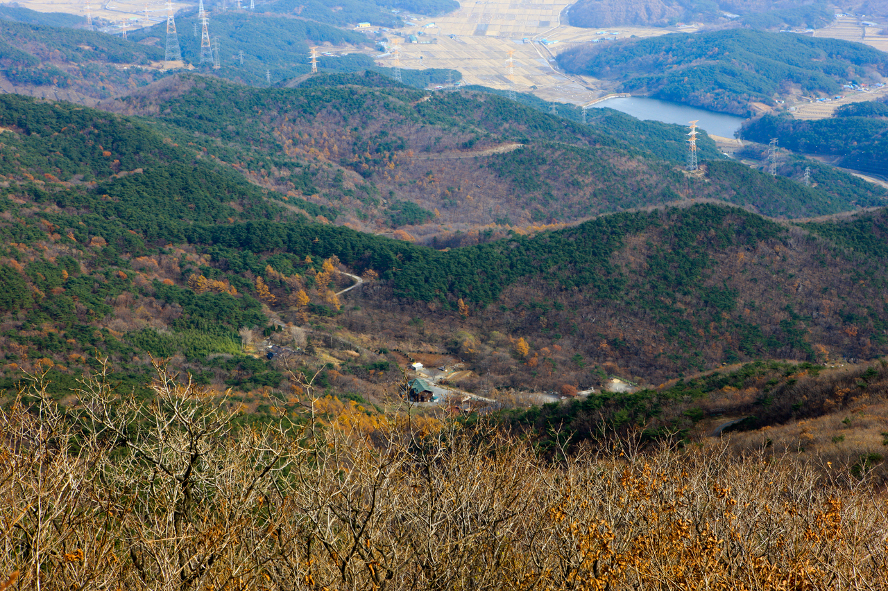 충남의 낮은 야산 능선이 겹겹이 이어지고 산자락 아래 농지와 저수지가 보이는 풍경