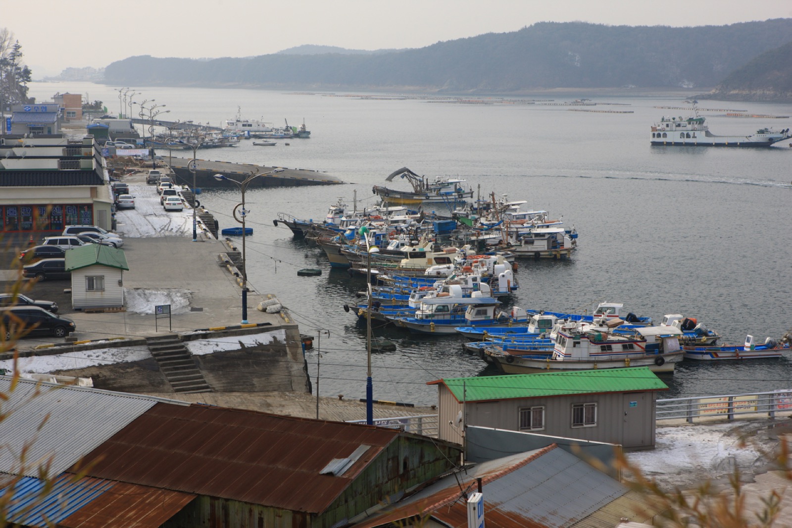 충남 보령 오천항, 녹슨 지붕 창고 너머로 어선들이 모여 정박한 겨울 포구 마을